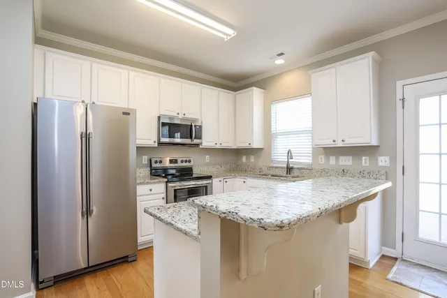 a kitchen with stainless steel appliances granite countertop a refrigerator a sink a stove a microwave and island