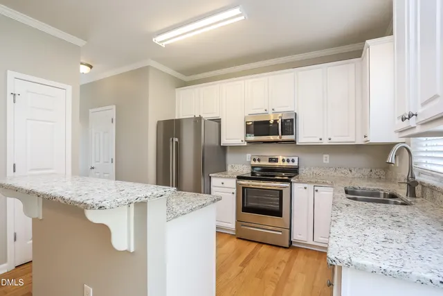 a kitchen with stainless steel appliances granite countertop a stove a sink dishwasher a refrigerator and a microwave