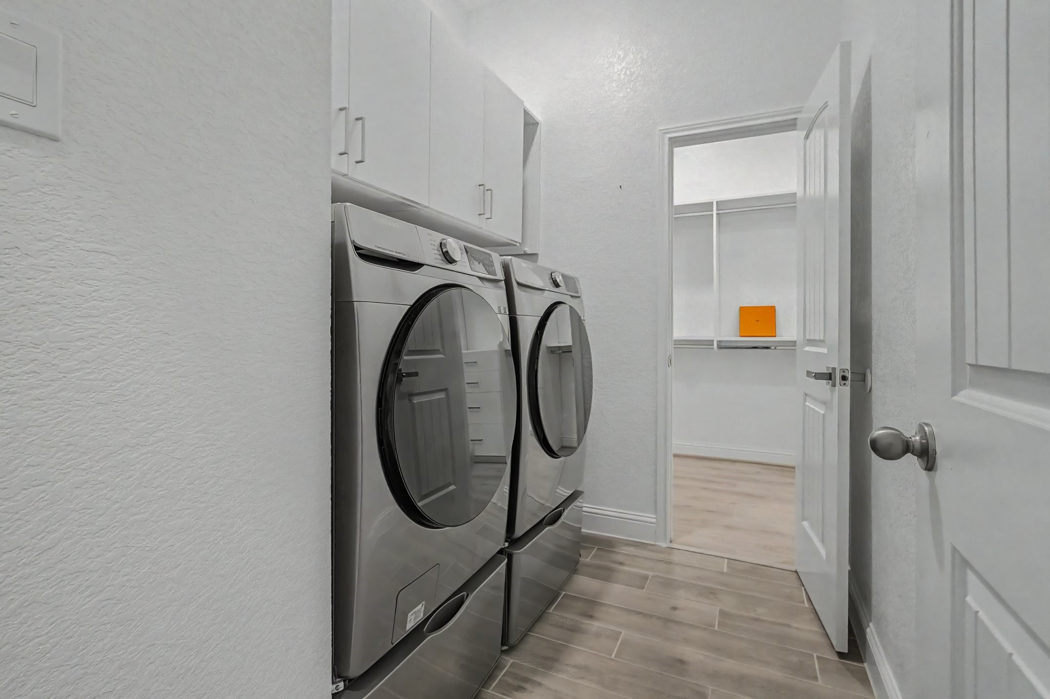 21339 Sierra Point Lane Porter, TX 77365 - Photo 23 of 36 Modern laundry room with a sleek washer and dryer set, overhead storage cabinets, and a tiled floor. The room opens to the master bedroom.