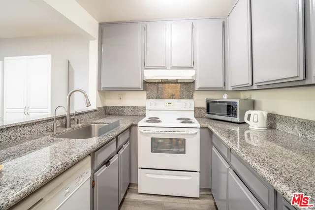 a kitchen with granite countertop a sink stove and cabinets