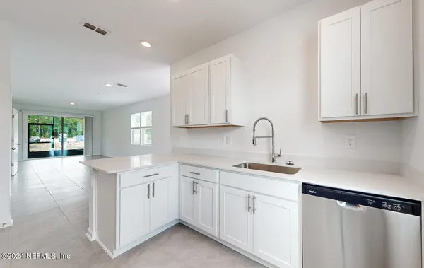 a kitchen with white cabinets sink and window