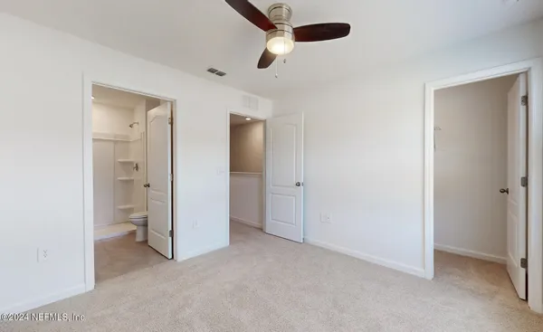an empty room with closet and a ceiling fan