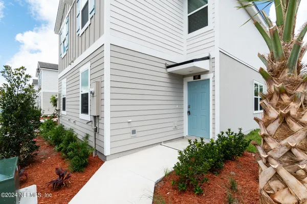 a view of a white house with a large windows and flower plants