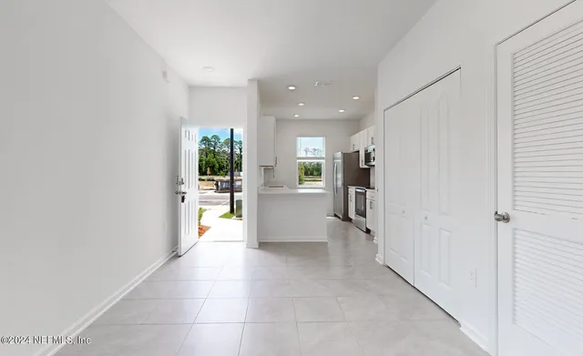 a view of a hallway with wooden floor and a kitchen