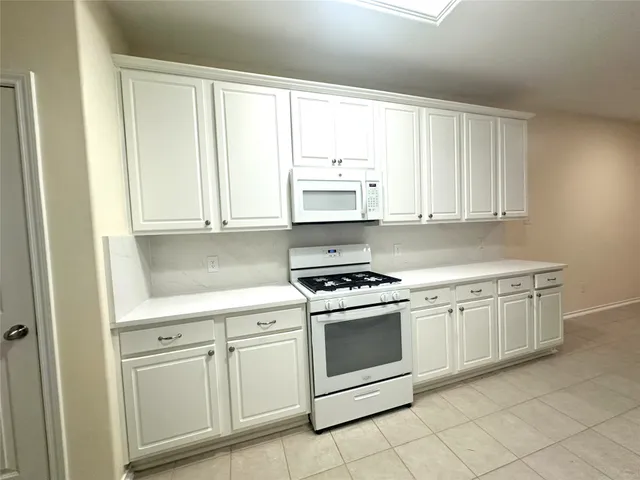 a kitchen with white cabinets and white appliances