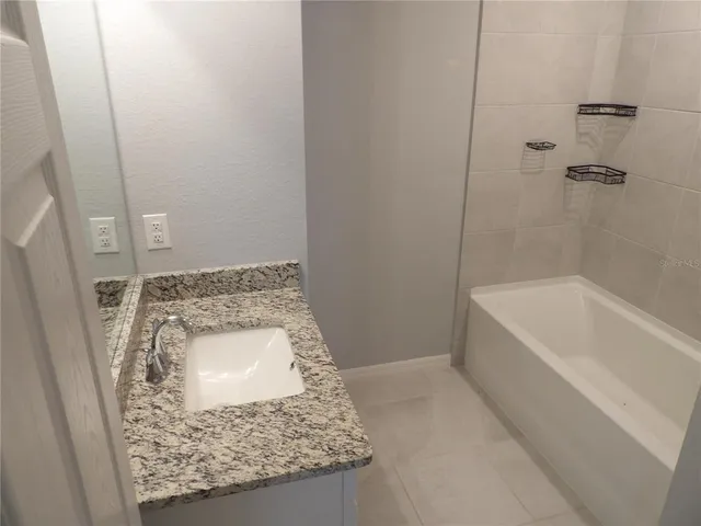 a bathroom with a granite countertop sink a mirror and bathtub