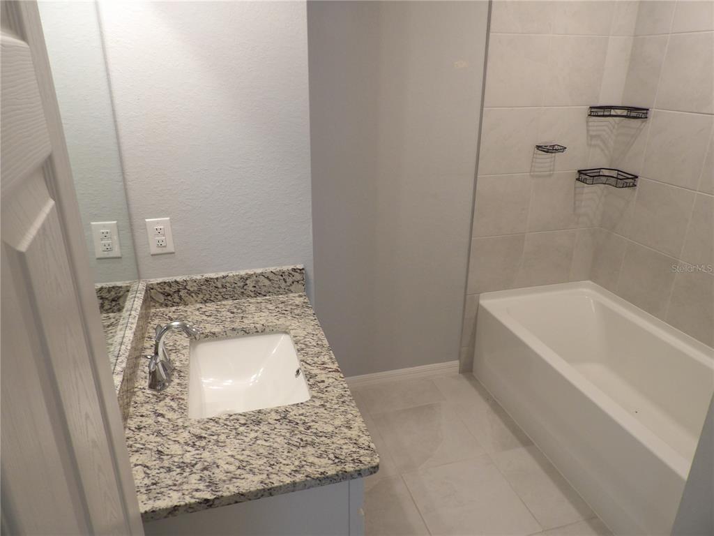 7653 Minardi Street North Port, FL 34291 - Photo 16 of 20 a bathroom with a granite countertop sink a mirror and bathtub