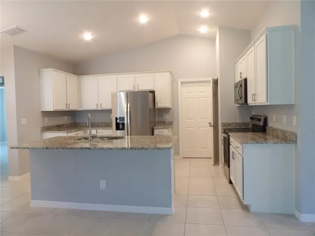 a kitchen with stainless steel appliances granite countertop a refrigerator a stove a sink and a refrigerator