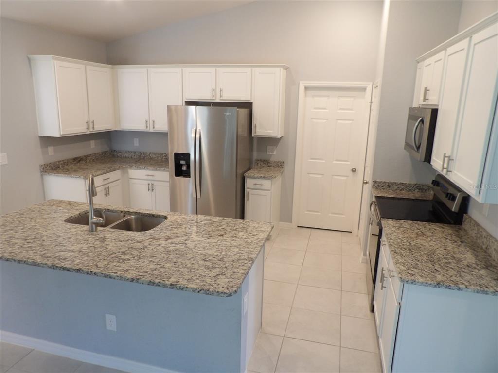 7653 Minardi Street North Port, FL 34291 - Photo 5 of 20 a kitchen with stainless steel appliances granite countertop a refrigerator a stove and a sink