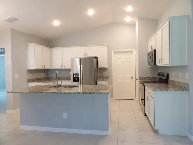 a kitchen with stainless steel appliances granite countertop a refrigerator a stove and a sink