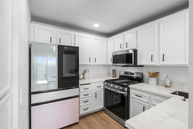 a kitchen with white cabinets and stainless steel appliances