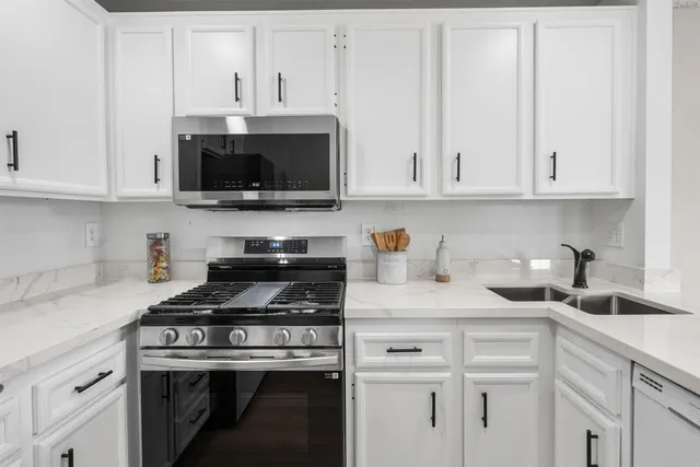 a kitchen with granite countertop white cabinets and a stove a sink