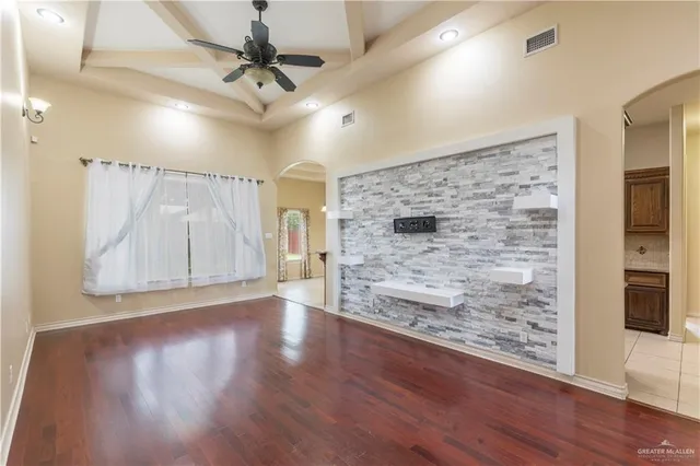 a view of a livingroom with wooden floor a ceiling fan and windows