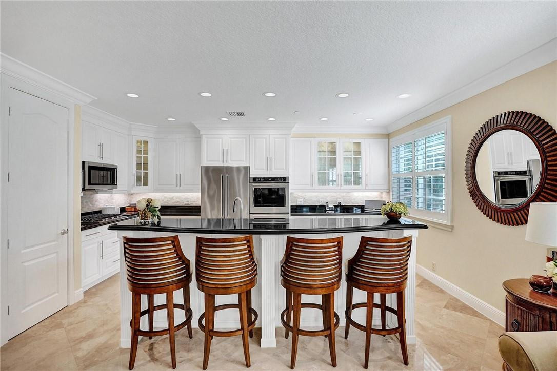 5565 Northeast Trieste Way, Unit 5565 Boca Raton, FL 33487 - Photo 17 of 44 a kitchen with stainless steel appliances granite countertop a table and chairs in it