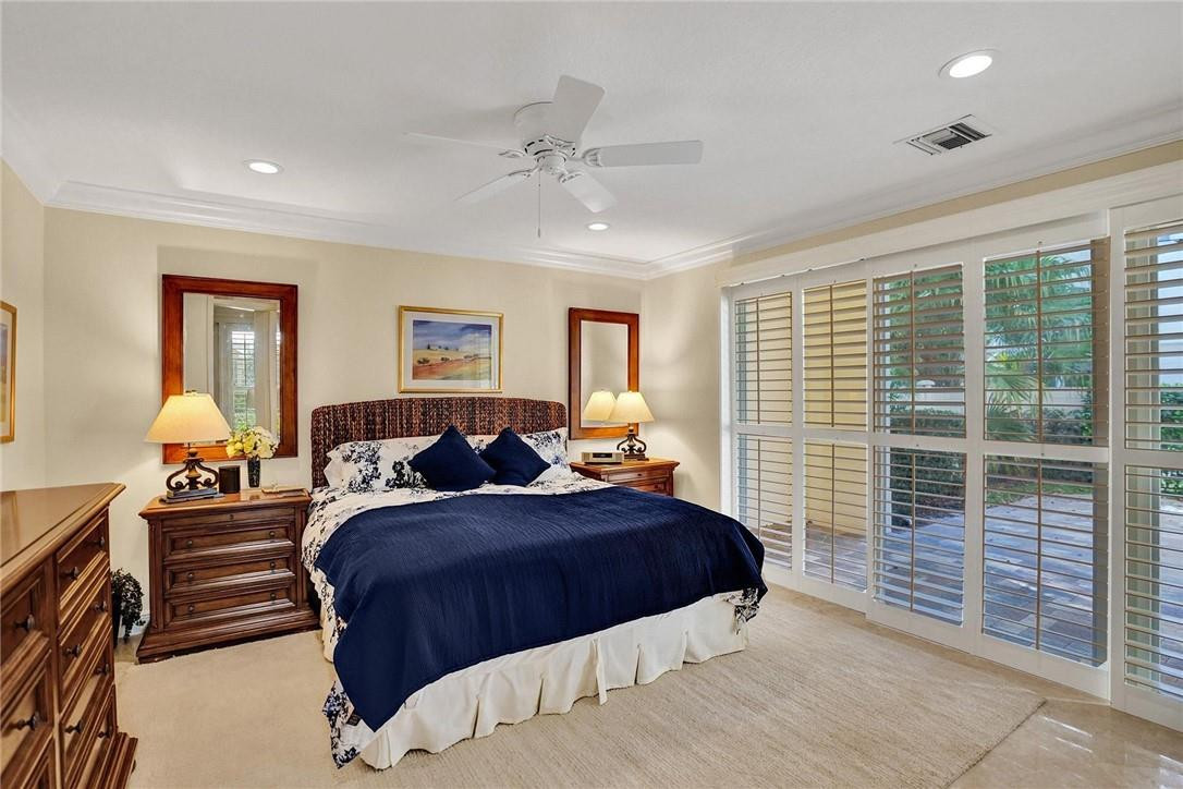 5565 Northeast Trieste Way, Unit 5565 Boca Raton, FL 33487 - Photo 7 of 44 a bedroom with a large bed and a chandelier