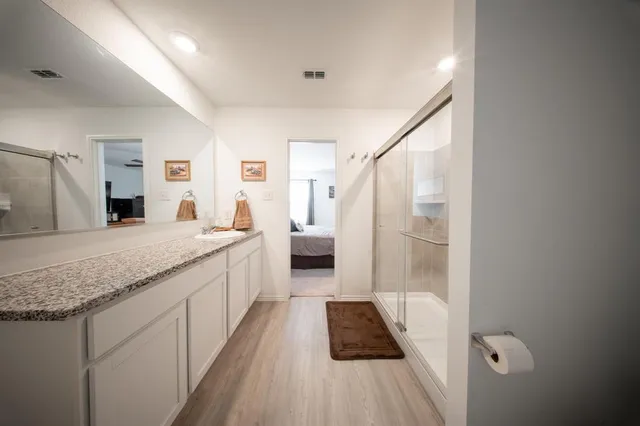 a bathroom with a granite countertop sink a toilet a mirror and shower