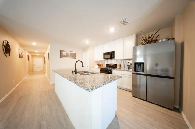 a large kitchen with a refrigerator a sink dishwasher and a stove with wooden floor