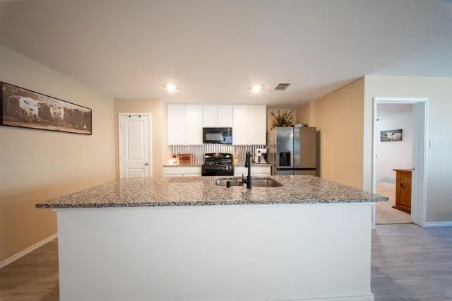 a kitchen with granite countertop a refrigerator a stove a sink and dishwasher