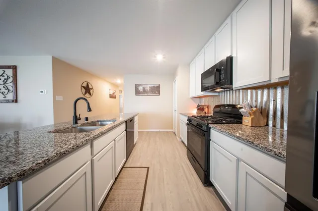 a kitchen with granite countertop a sink and a stove top oven