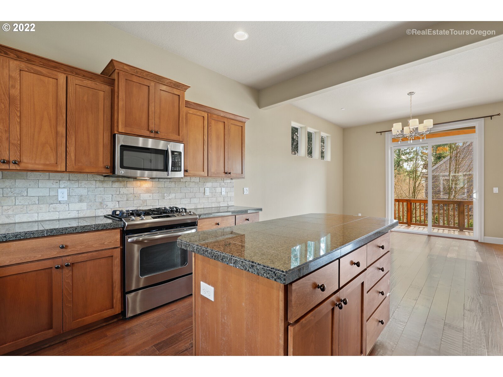 11510 Northwest Knightsview Lane Portland, OR 97229 - Photo 11 of 32 a kitchen with stainless steel appliances granite countertop a sink dishwasher stove and microwave with wooden cabinets