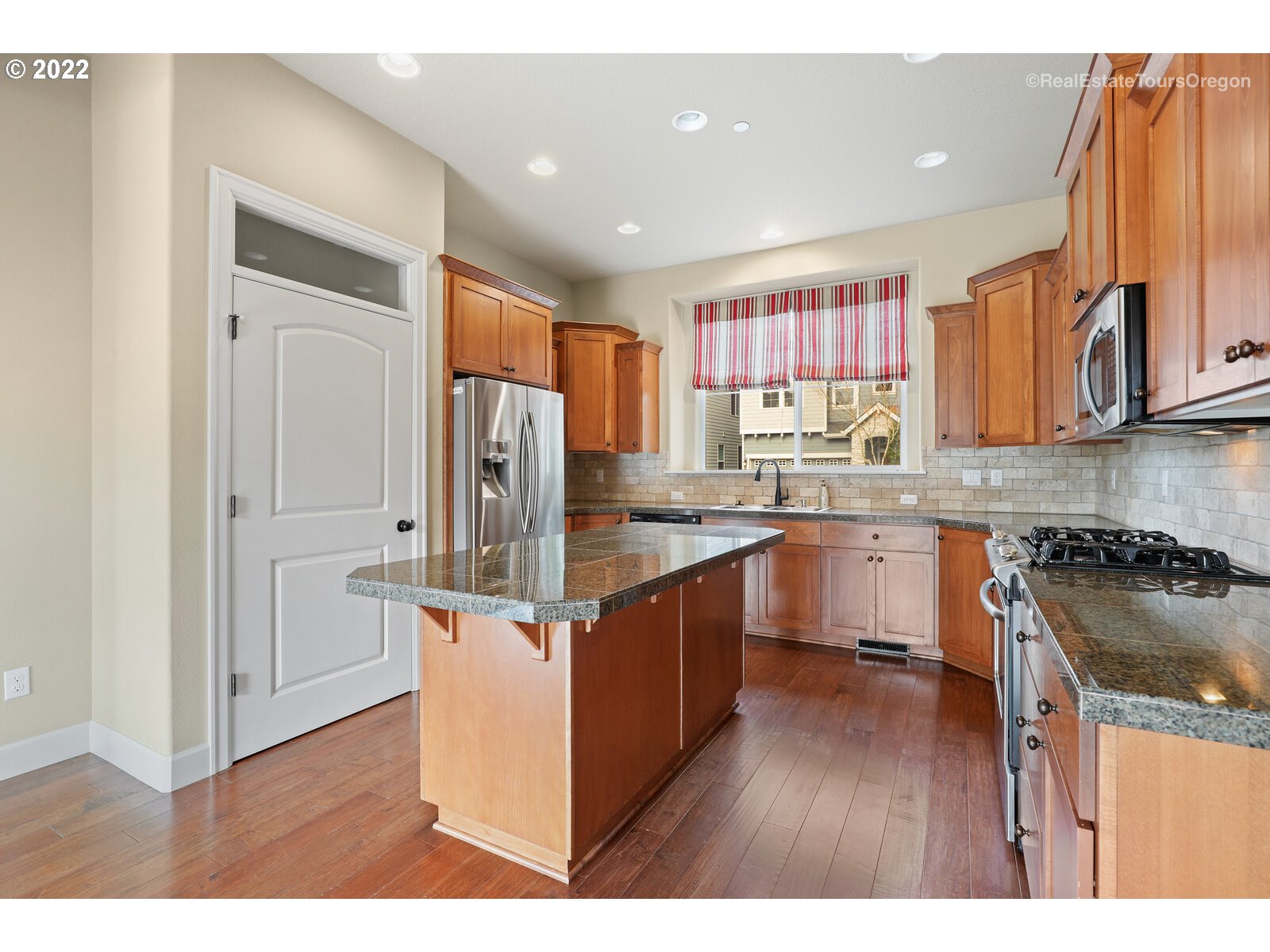 11510 Northwest Knightsview Lane Portland, OR 97229 - Photo 10 of 32 a kitchen with stainless steel appliances granite countertop a refrigerator a sink dishwasher a stove with wooden cabinets and floor