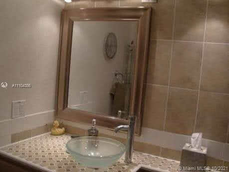 195 Fanshaw East, Unit 195 Boca Raton, FL 33434 - Photo 8 of 12 a bathroom with a granite countertop sink a mirror and shower