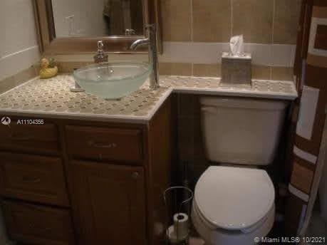 195 Fanshaw East, Unit 195 Boca Raton, FL 33434 - Photo 9 of 12 a bathroom with a granite countertop toilet sink and mirror