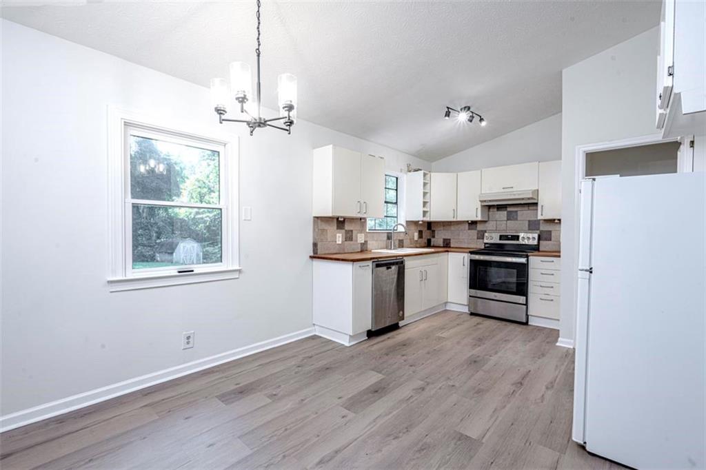 1752 Mitzi Court Duluth, GA 30097 - Photo 23 of 41 a kitchen with granite countertop a refrigerator a sink dishwasher a stove and white cabinets with wooden floor