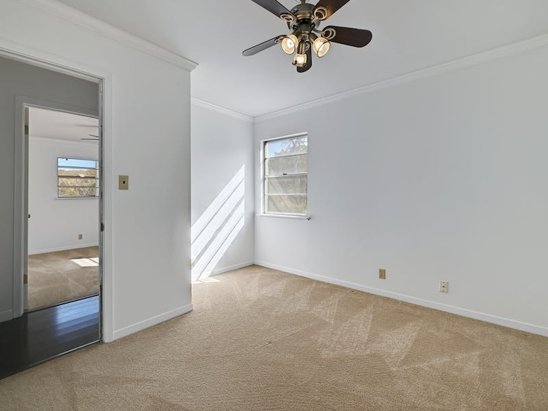 1802 Temple Drive Austin, TX 78721 - Photo 17 of 20 Unfurnished room featuring crown molding, light carpet, and a ceiling fan