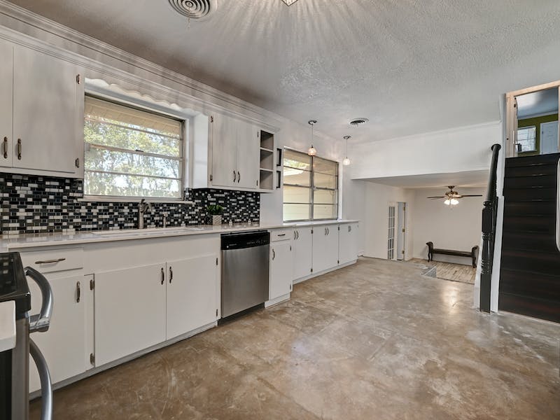 1802 Temple Drive Austin, TX 78721 - Photo 5 of 20 Kitchen featuring stainless steel appliances, tasteful backsplash, white cabinetry, open shelves, and a textured ceiling