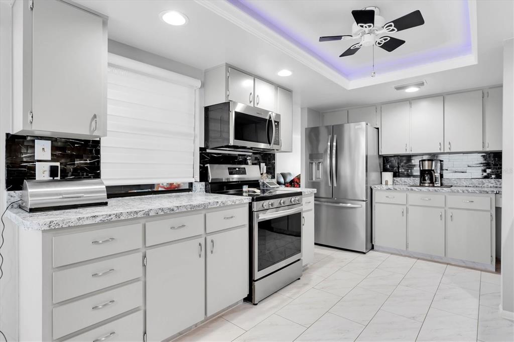 7099 Pond View Court Spring Hill, FL 34606 - Photo 13 of 64 a kitchen with granite countertop a sink stainless steel appliances and cabinets