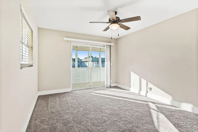 an empty room with windows and fan