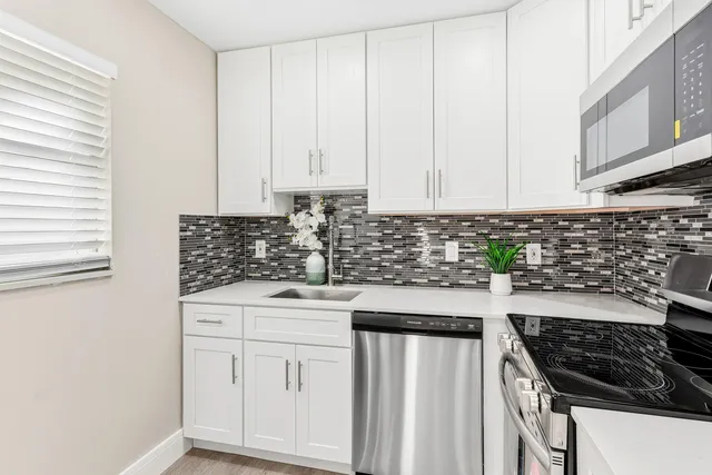 a kitchen with white cabinets a sink and dishwasher