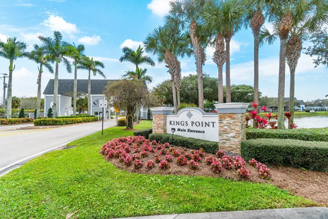a view of a sign board with a big yard and potted plants