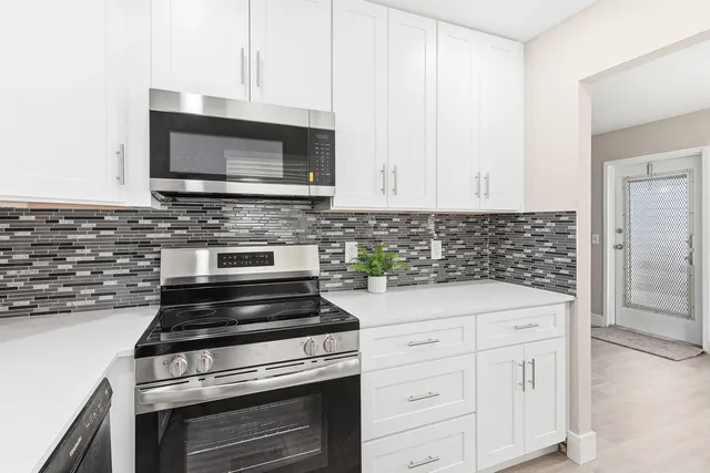 a kitchen with white cabinets and stainless steel appliances