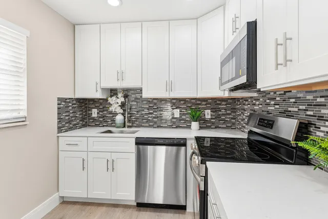 a kitchen with stainless steel appliances a stove a white cabinets and a sink