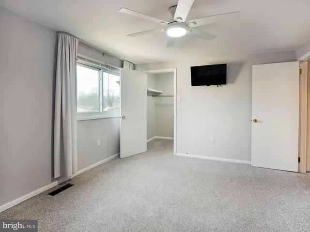 an empty room with windows and ceiling fan
