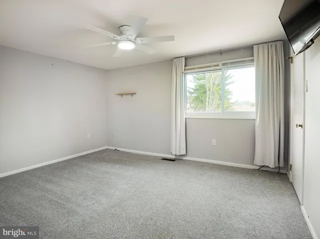 an empty room with a window and a ceiling fan