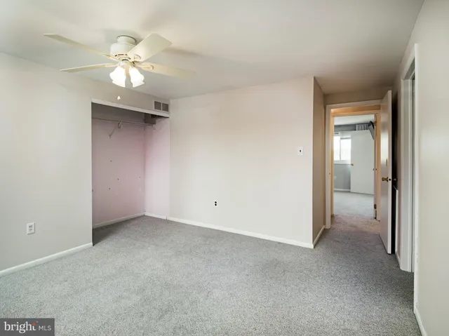 an empty room with a chandelier fan and a bathroom