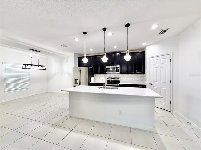 a large kitchen with kitchen island white cabinets and stainless steel appliances