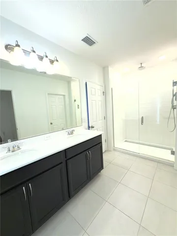 a bathroom with a double vanity sink mirror and shower