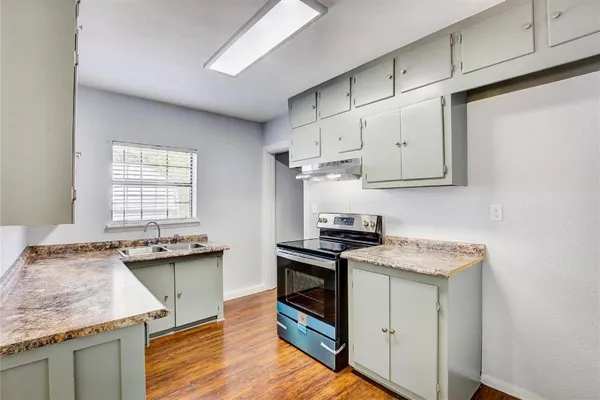 a kitchen with granite countertop stainless steel appliances sink stove and cabinets