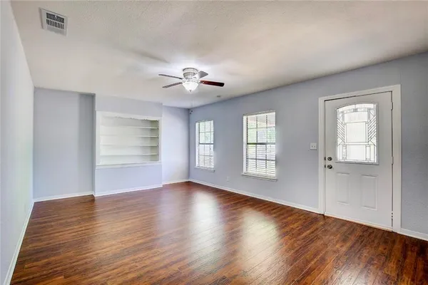 a view of an empty room with a window and wooden floor