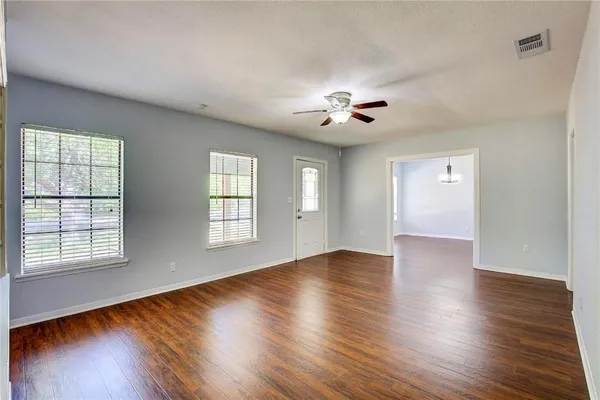 a view of an empty room with a window and wooden floor