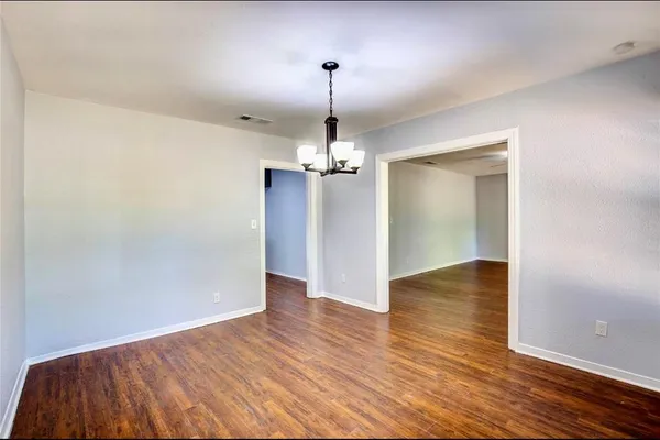 a view of a room with wooden floor chandelier and a window