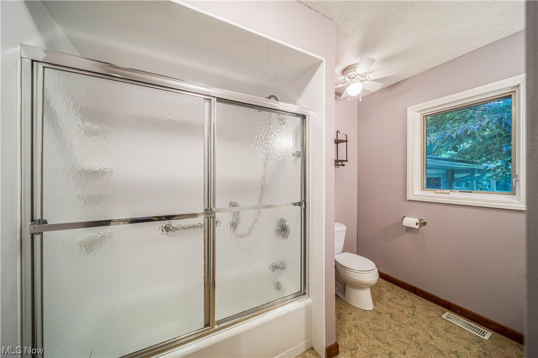 7585 Middle Ridge Road Madison, OH 44057 - Photo 5 of 35 Bathroom with combined bath / shower with glass door, ceiling fan, a textured ceiling, and toilet