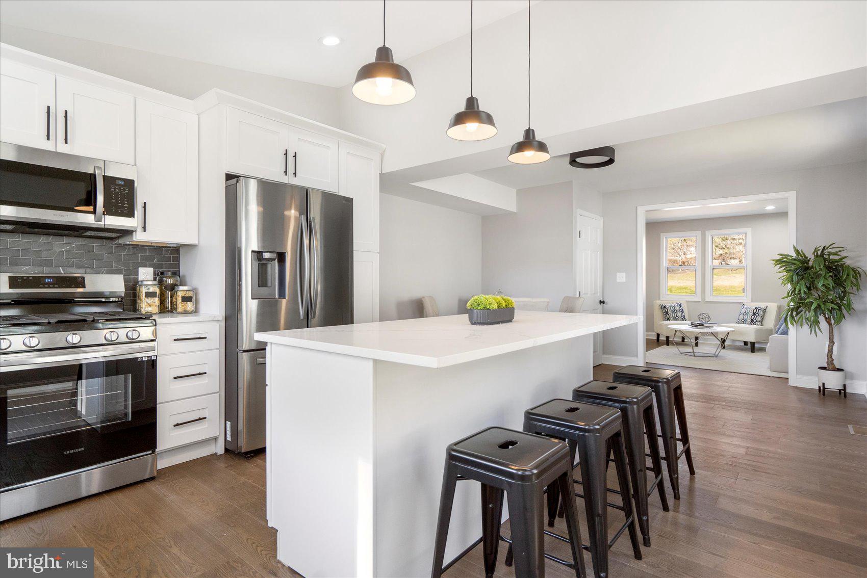 a kitchen with stainless steel appliances a white center island a stove a dining table and chairs