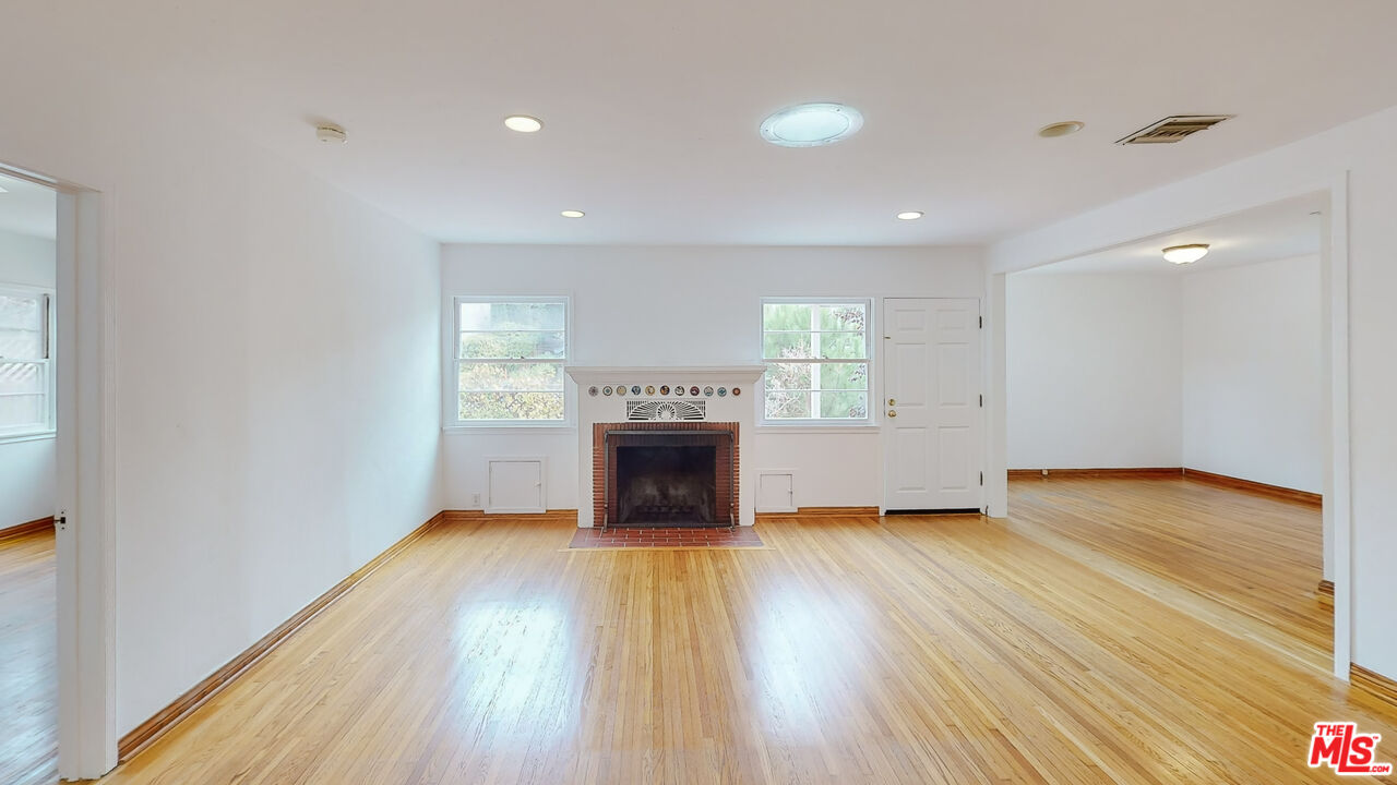 365 Sycamore Road Santa Monica, CA 90402 - Photo 7 of 42 an empty room with wooden floor fireplace and windows