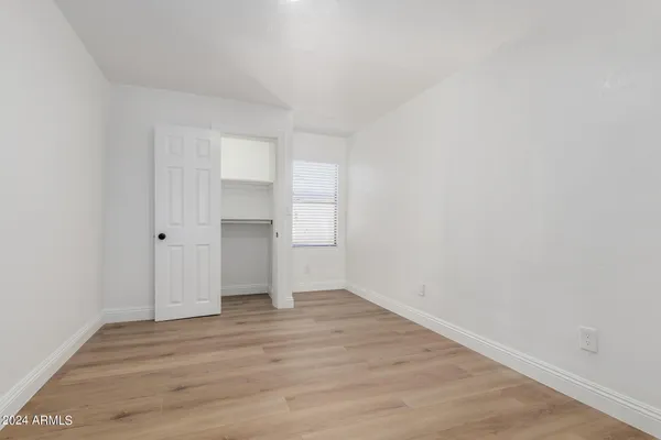 a view of empty room with wooden floor and window