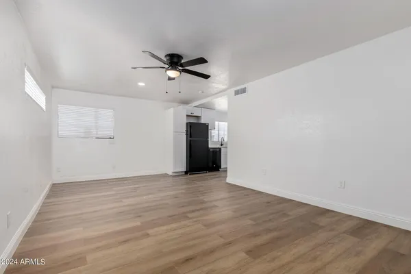 a view of empty room with wooden floor and ceiling fan